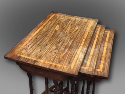 A fine George III Nest of three Tables in Kingwood with Satinwood crossbanding, on elegant turned legs supported by bow stretchers and standing on scrolled feet of unusual design top details